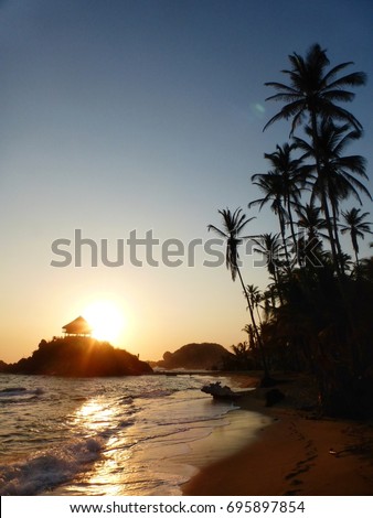a beautiful sunrise over a wooden hut built on an island in the Tayrona National Park in Colombia, South America