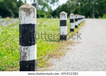 Milestones - Black and white milestones with green grass roadside, Trees roadside in background . concept for next step. Next station.Up level.