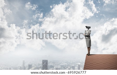 Faceless businesswoman with camera zoom instead of head standing on house roof