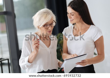 Happy positive woman showing her colleague a document