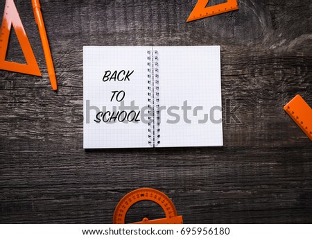 Notebook, pen, ruler, straightedge and protractor on wooden background with inscription back to school, Nobody, flat lay
