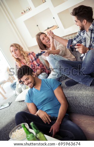 Friendship, technology, games and home concept - smiling  friends playing video games at home.