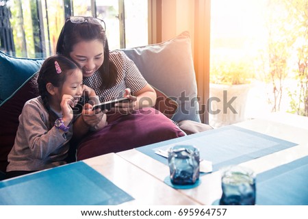 Asia mother and daughter or kid enjoy playing smartphone, happy family using mobile phone Royalty-Free Stock Photo #695964757
