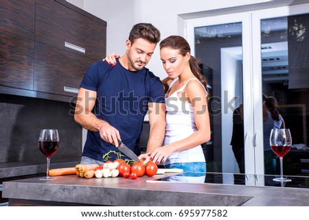 Beautiful young couple cooking while enjoying a glass of wine in the kitchen.