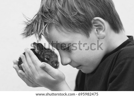 Little boy with cute, tiny, grey bunny on his hands (black and white)
