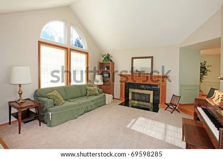 Living room with green sofa, large window and piano