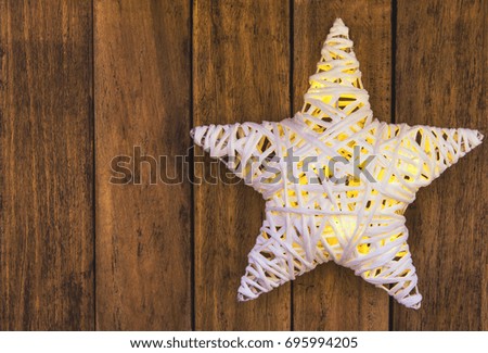 Rattans shining white Christmas star on weathered plank wood background, copy space for text. Template for greeting card, poster.