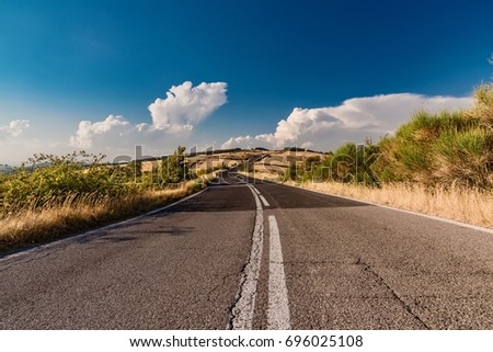 Road in deserted nature with warm summer colors in Italy