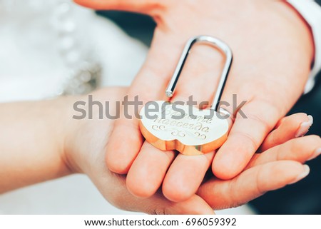 Wedding Lock as Symbol of Marriage in Hands of Bride and Groom with an Inscription in Russian translated as Together Forever