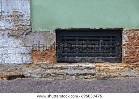one window with an iron lattice to the cellar of the old house on the destroyed brick wall