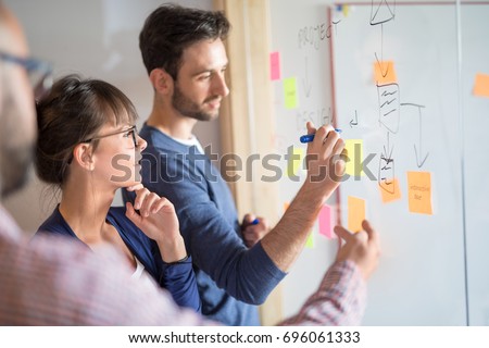 Business people meeting at office and use post it notes to share idea. Brainstorming concept. Sticky note on glass wall. Royalty-Free Stock Photo #696061333