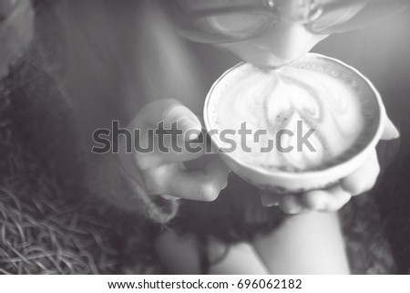 Close up young asian woman drinking or taste coffee or cocoa. holding a ceramic cup of hot latte art coffee or hot cocoa. selective focus. filtered image to vintage black and white.