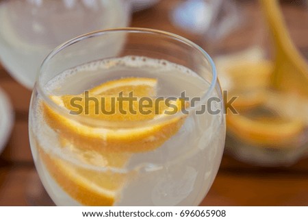 Close up photo with shallow depth of field of a refreshing tasty summer lemonade with orange slices in it, freshly prepared for a garden party. Vivid colors that represent joyful summer vibes.