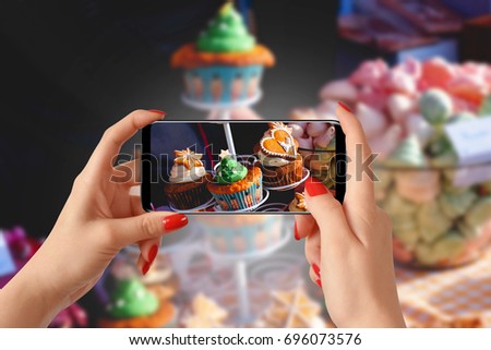 Woman hands taking photo of cupcakes with smartphone
