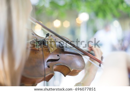 abstract girl with blond hair  playing on a violin in spring park. 