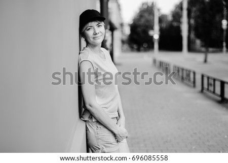 Young stylish blonde woman in shorts and black cap. Urban concept. Black and white