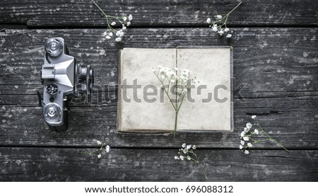 Photo camera, diary and flowers on a wooden background
