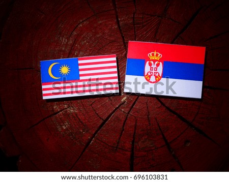 Malaysian flag with Serbian flag on a tree stump isolated