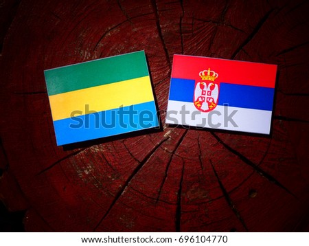 Gabon flag with Serbian flag on a tree stump isolated