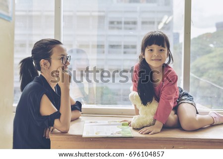 Beautiful girl doing and learning tale homework  with mother with high wide window against city view.Split tone instagram like process.