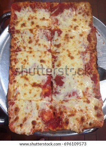 Delicious Long Island Sicilian pizza on  table.  Instagram mobile pic picture is taken of pizza and published on social media, Facebook and Instagram and Snapchat. Pizza contains cheese, sauce, dough