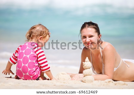 Mother and daughter making sand castle at tropical beach