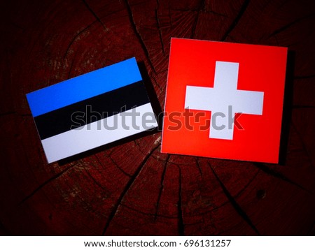 Estonian flag with Swiss flag on a tree stump isolated