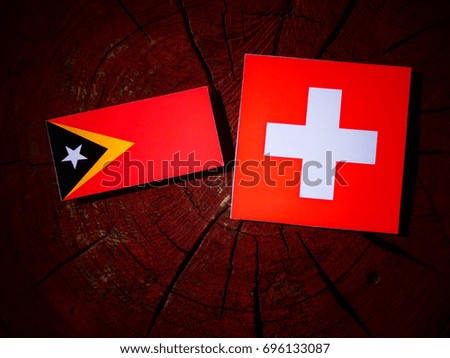 East Timorese flag with Swiss flag on a tree stump isolated