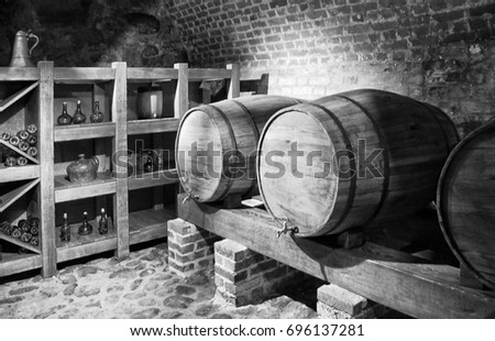 Barrels with a wine in a cellar with a brick wall background. Black and White Photography. Beautiful vintage. 