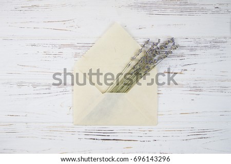 Bouquet of lavender flowers in a paper envelope on a wooden white background. romantic background