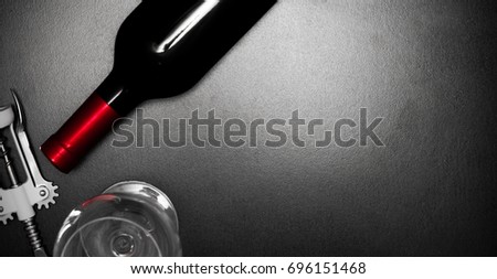 Bottle of red wine, an empty wine glass and a corkscrew on a dark background of a stone table. Top view. Space for text.