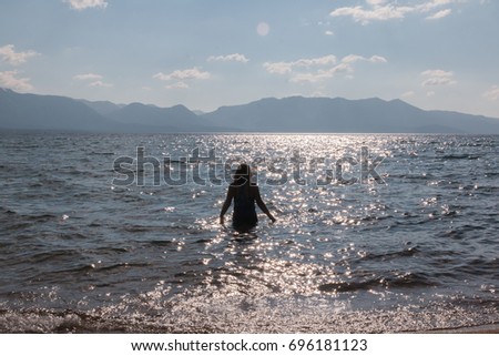 Silhouette of One Young Girl With Raised Arms in the Water at the Beach