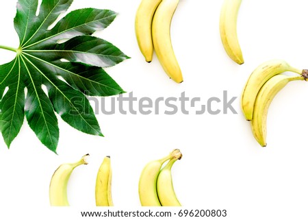Exotic fruits. Fresh ripe bananas near big tropical leaf on white background top view copyspace