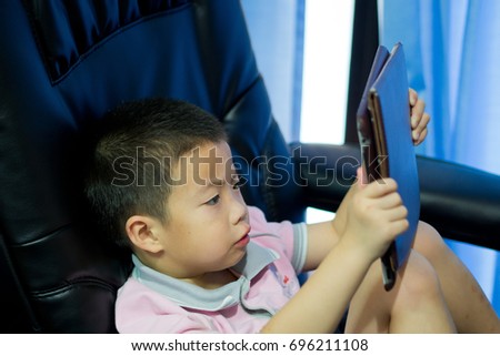 asian children boy watching tablet  / playing phone and looking at cartoon
