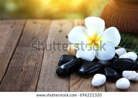 flower frangipani on wood background and stone spa.
