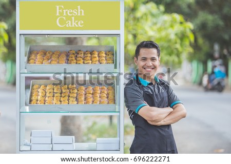 small business owner standing proudly in front of his food stall. street food concept Royalty-Free Stock Photo #696222271