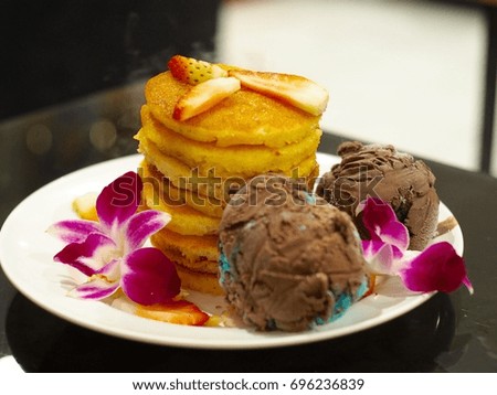 Pancakes with ice cream topped with strawberries, close up