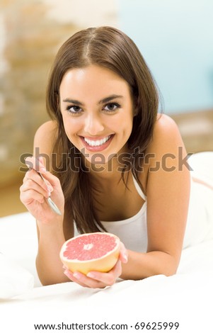 Portarit of young woman eating grapefruit at home
