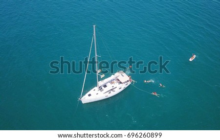 sailboat yacht on open ocean with people having fun jumping into the water
