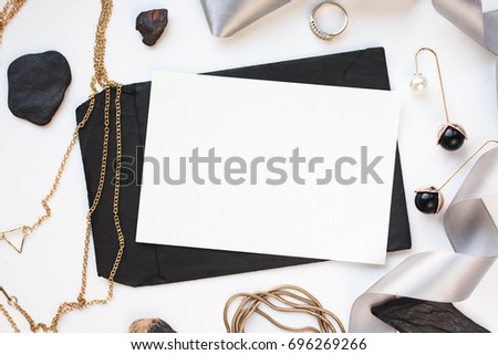 Mockup on a white background with a black envelope, white card and gold elements. Gold necklace. gold chain. ribbon. 
