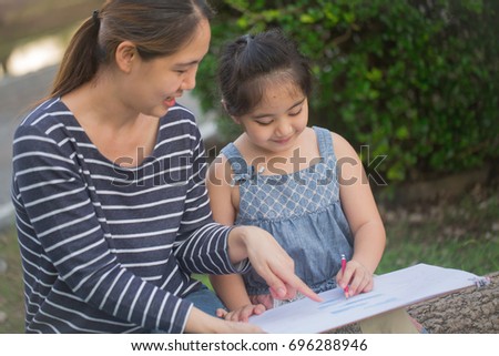 Happy Asian Daughter drawing picture with mother together in the park