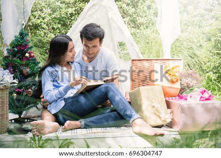 A picture of a young couple with a present in the park celebrate Christmas time, hot tropical Christmas