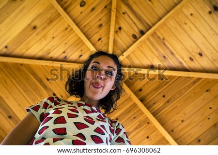 Portrait of young and attractive woman from low angle. Wooden ceiling looks like a star around her head.