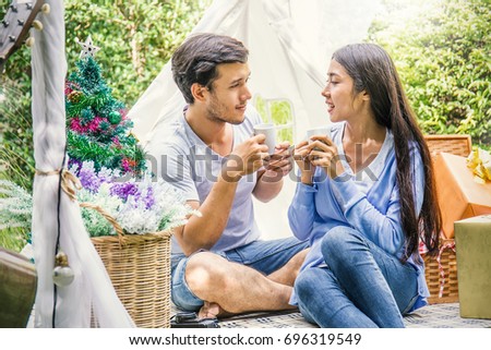 A picture of a young couple drinking coffee with a present in the park celebrate Christmas time, hot tropical Christmas