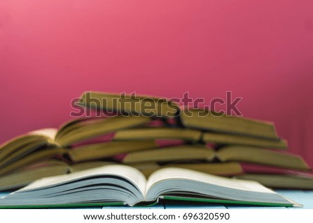 Textbooks and books on a blue wooden table. Beautiful pink background.