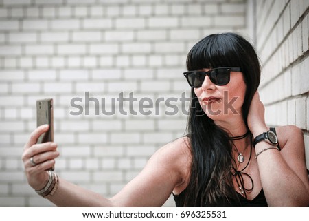 Woman taking a selfie near a brick wall