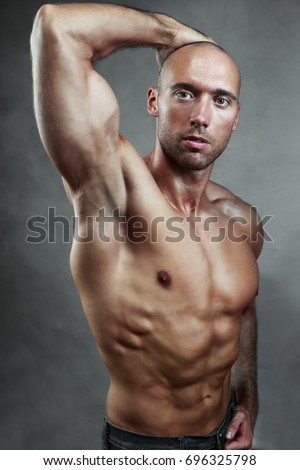 athletic muscule man shows his biceps studio shot over dark background