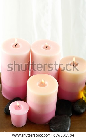Black stones and set of candles on wooden background