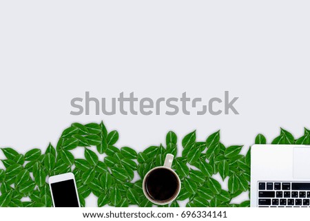 Creative layout of leaves. Frame made of laptop, a mug of coffee, smart phone and green leaves. Flat lay, top view, copy space