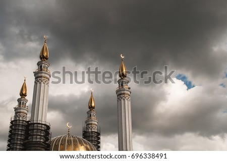 Muslim mosque with Crescent moon on the spire, a historic landmark, the minaret on the background of sky with clouds, cumulonimbus clouds, concept clouds over Islam